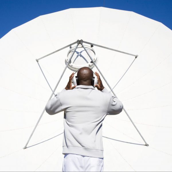 Man facing satellite dish with hands on earphones, Cape Town, Western Province, South Africa