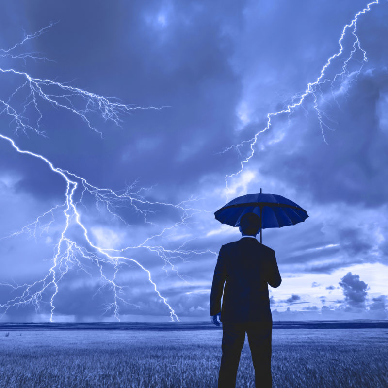 Man in black suit with a black umbrella in a storm
